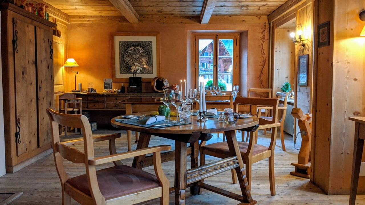 Speisesaal im Restaurant les Jardins de la Tour in Rossinière, Pays-d'Enhaut, Schweiz. Das Bild zeigt den Speisesaal. Im Vordergrund die Holzstühle und der Esstisch.