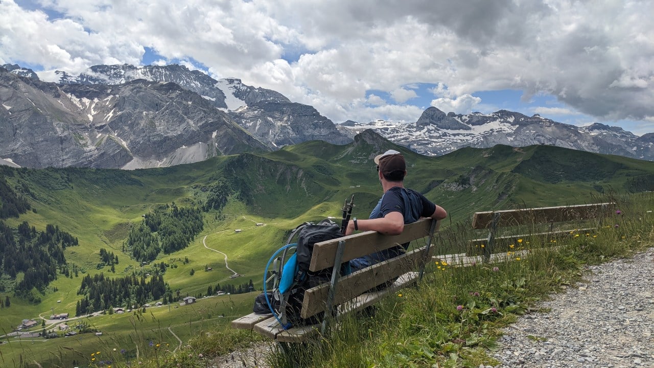 Matthias schaut auf den Wildstrubel vom Blumenweg in Adelboden, Schweiz aus. Unter ihm liegt Gleis und die Via Alpina Wanderroute.
