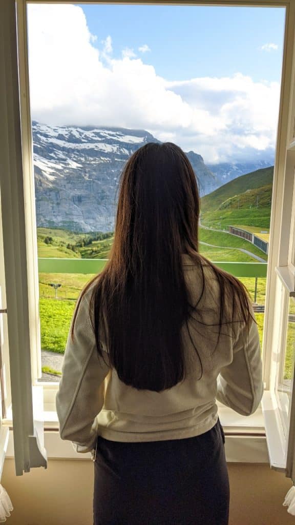 Solène looking out of the window at hotel Bellevue des Alpes on Kleine Scheidegg in Switzerland