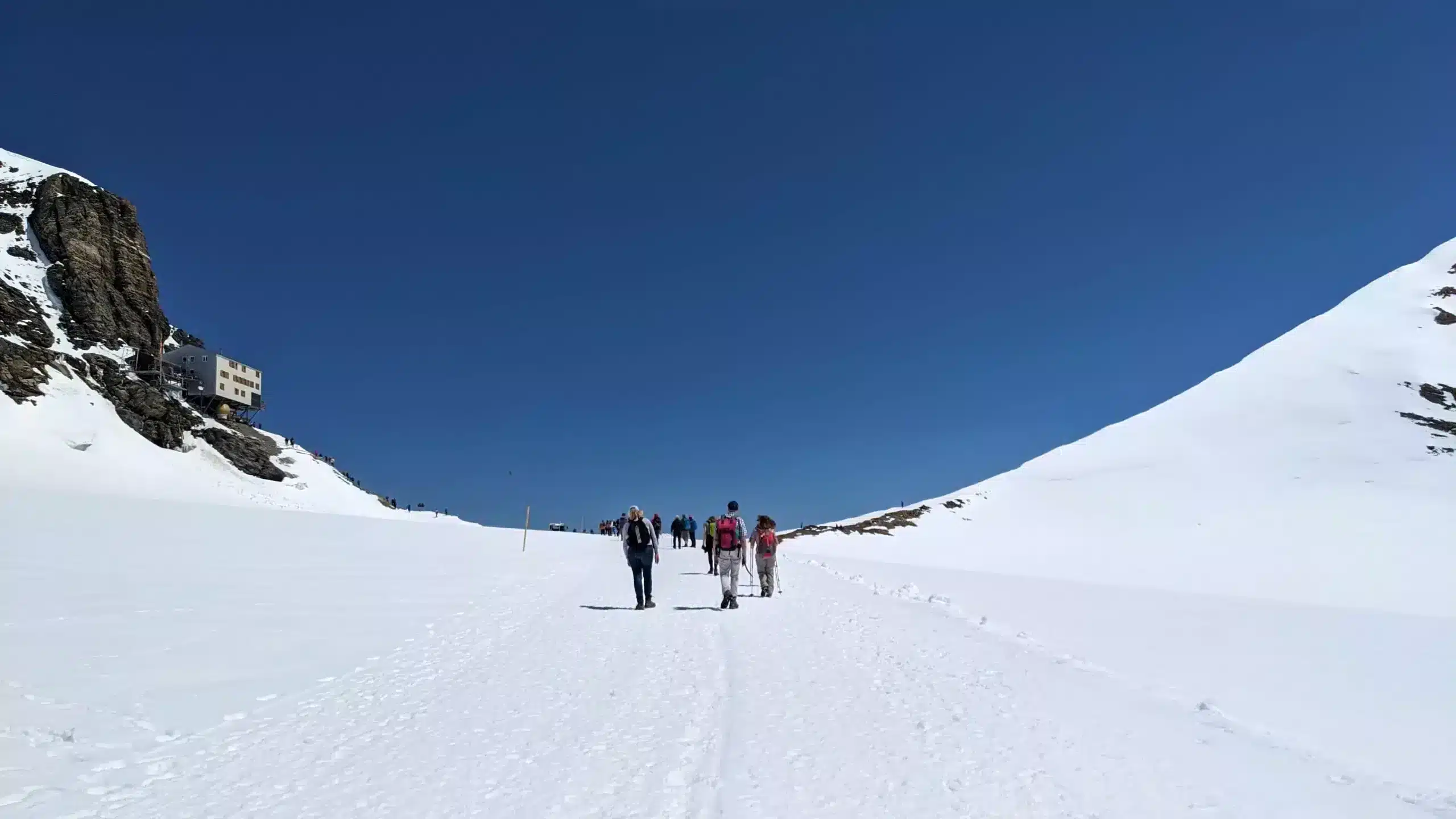 Wanderweg über ein Schneefeld vom Jungfraujoch zur Mönchsjochhütte. Links sieht man die Mönchsjochhütte.
