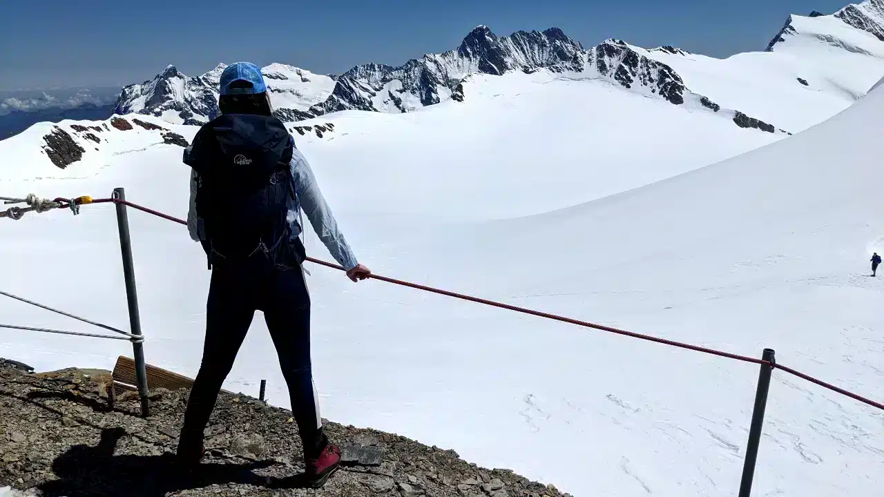Solène steht vor der Mönchsjochhütte und blickt auf die Alpen