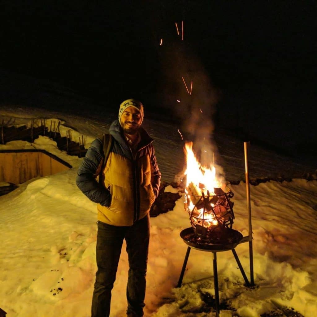 Matthias beim wärmt sich bei der Feuerschale vor dem Restaurant Hohliebestübli in Adelboden auf.