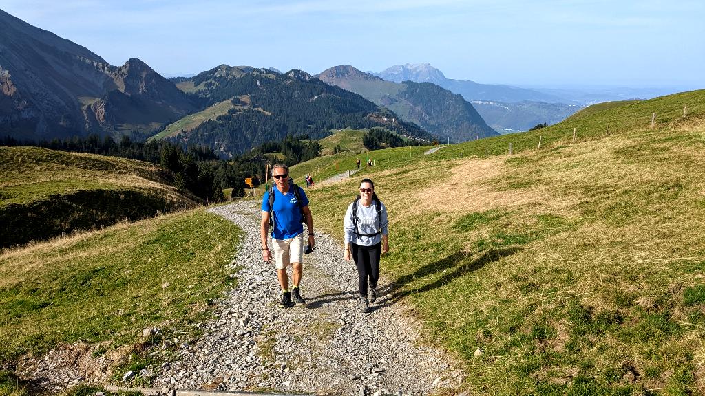 Marc et Solène randonnent sur un large chemin de gravier vers l'Alp Tritt sur Niederbauen
