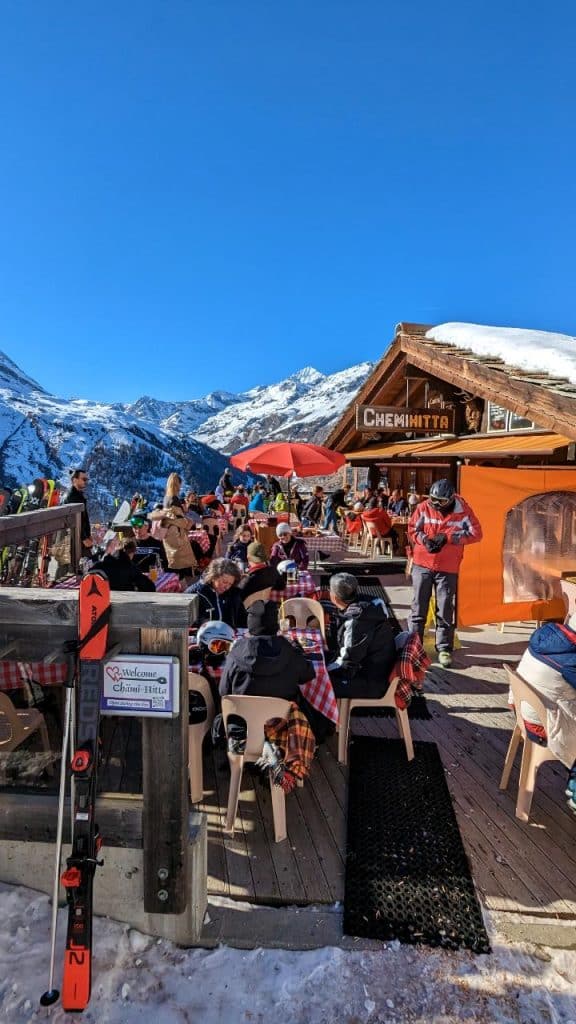 The terrace of the Chämi-Hitta restaurant in winter on the Riffelalp-Zermatt hike. In the background mountains and blue clear sky.