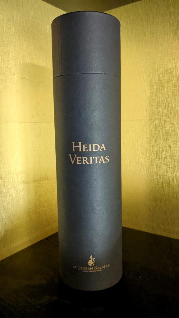 Eine zylinderförmig eingepackte Weinflasche der St. Jodern Kellerei mit der Aufschrift "HEIDA VERITAS"