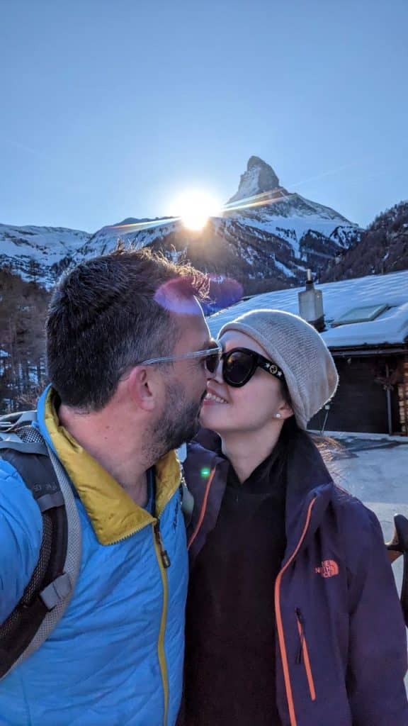 Solène and Matthias kiss in front of the sun setting behind the Matterhorn.