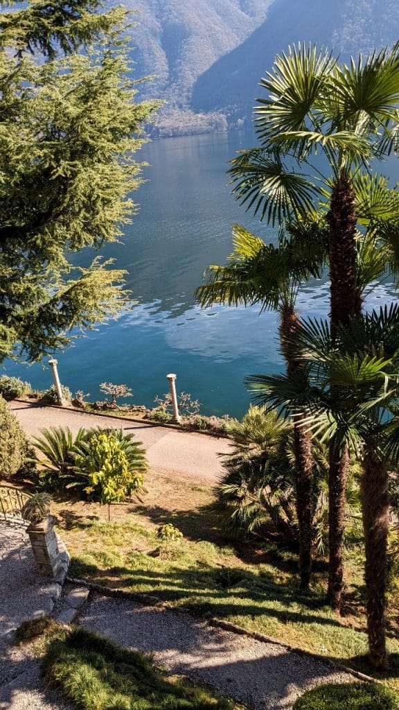 If you hike the Sentiero dell'olivo visit the park Villa Heleneum. View from Villa Heleneum Park on Lake Lugano and palm trees.