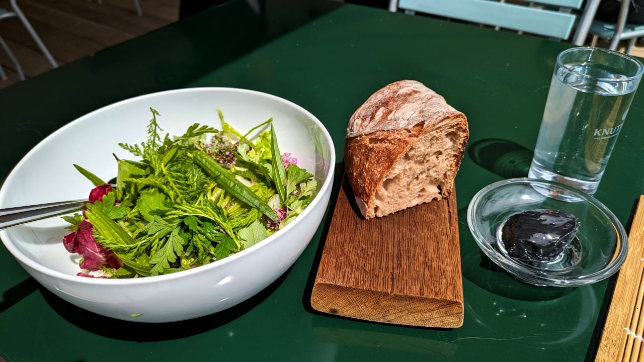 Salat mit frischen Kräutern, Sauerteigbrot und Kohle-Butter in der Weitsicht aus dem Bramboden
