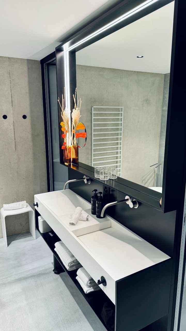Das Badezimmer im Hotel des Horlogers in erdigen Farbtönen und grossem Spiegel