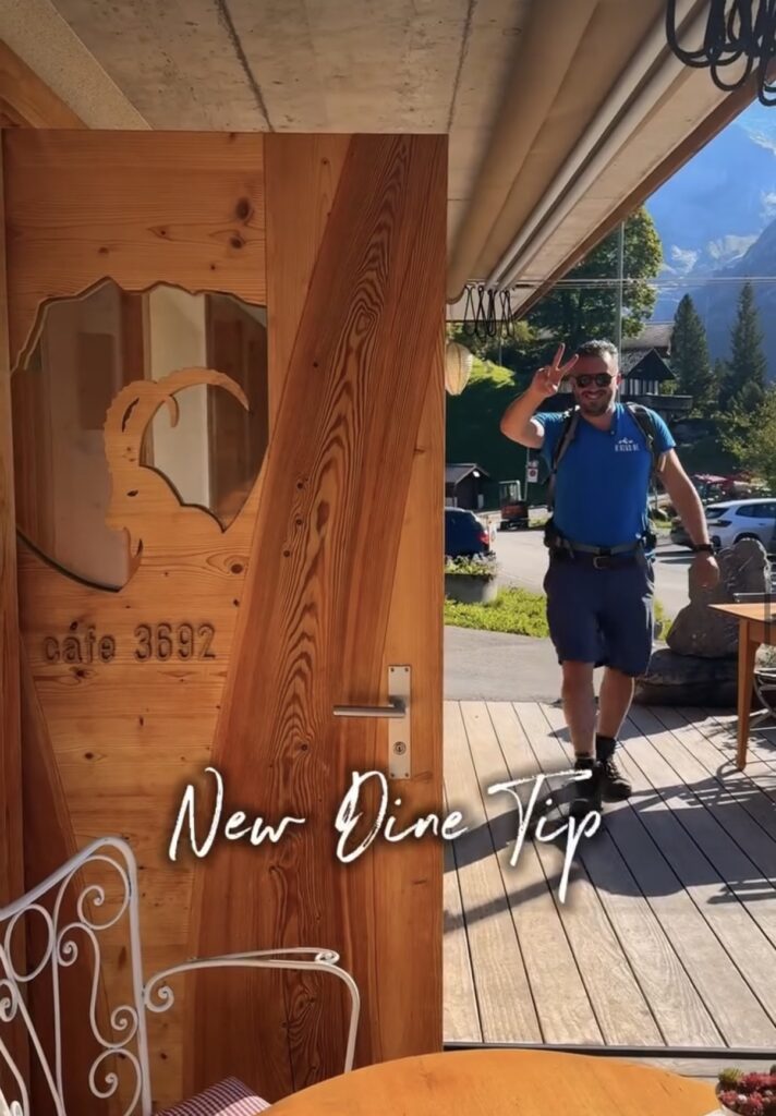 Matthias von Hike&Dine betritt das Café 3692 in Grindelwald durch die markante Altholztür mit Steinbock-Schnitzerei. Neuer Dine-Tipp am Sonnenhang.
