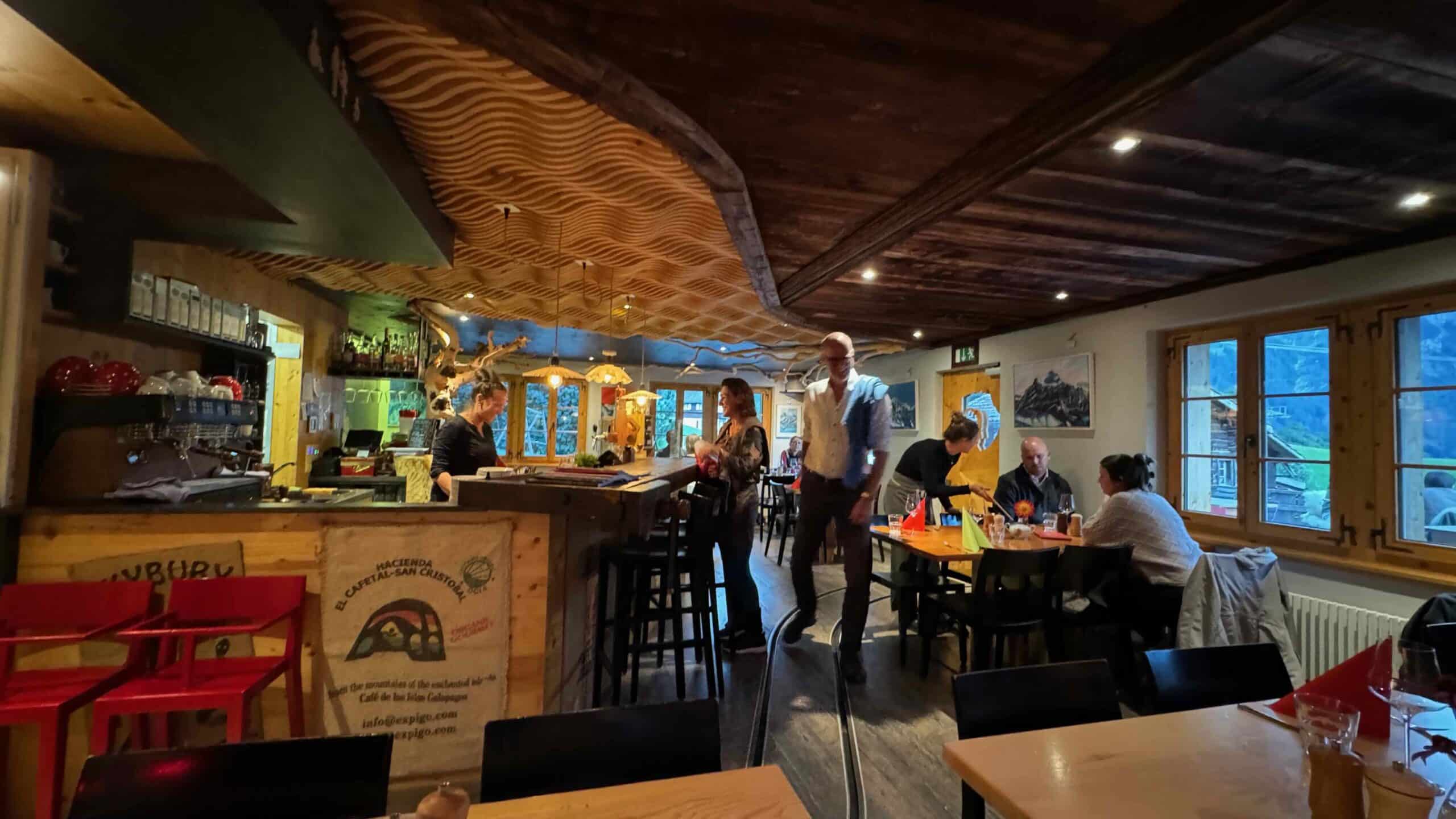 Blick in das Café 3692 mit Gästen, der handgefertigten Holzdecke von Bruno Kaufmann und gemütlicher Beleuchtung.
