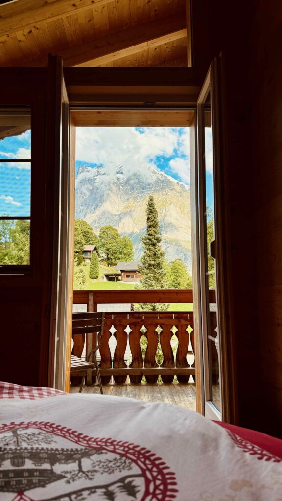 Blick aus einem Gästezimmer im Café 3692 durch die Balkontür auf die verschneite Eiger-Nordwand in Grindelwald.