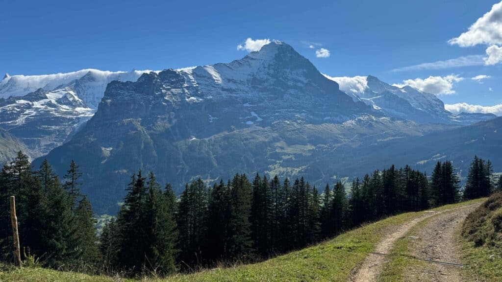 Nahaufnahme der massiven Eiger-Nordwand mit Schneefeldern und Wolkenresten in den Berner Alpen.