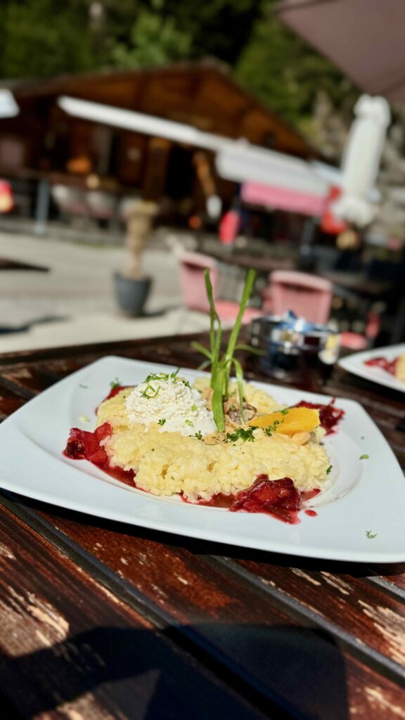 Ein Teller cremiges Risotto, garniert mit Kräutern und Beeren, serviert auf der Terrasse des Rasthysi in Grindelwald.