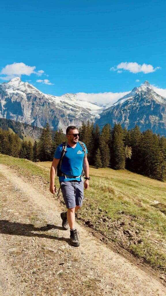 Matthias wandert einen Schotterweg entlang, im Hintergrund die hohen Berge der Jungfrau-Region.